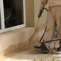 General pest control technician spraying exterior perimeter around a home in Ogden, UT
