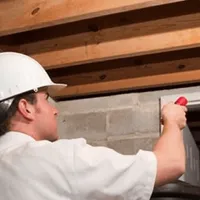 Termite inspection technician checking a basement wall and framing for termite activity in Ogden, UT